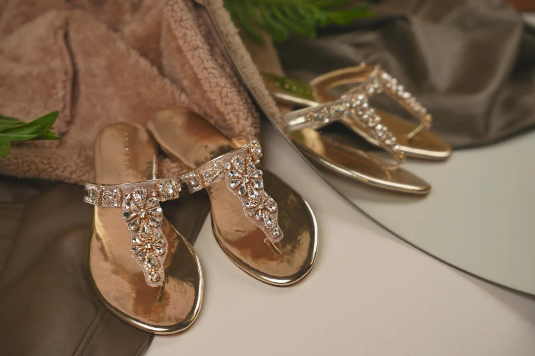 Elegant embellished gold sandals from Opia’s Exclusive Ramadan Fest collection displayed on reflective surface with soft fabric background