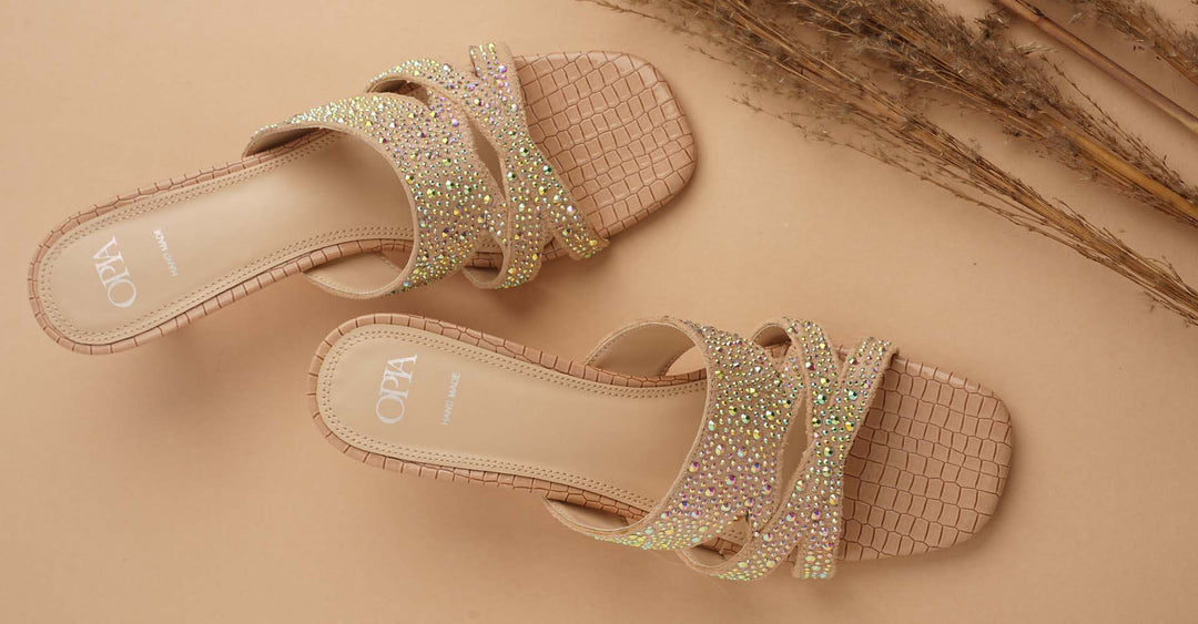 pair of beige women's heels with sparkling rhinestone straps on a neutral background